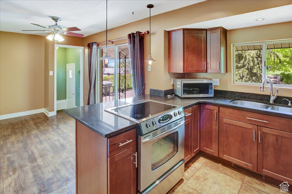 Kitchen featuring decorative light fixtures, ceiling fan, stainless steel appliances, sink, and light tile floors