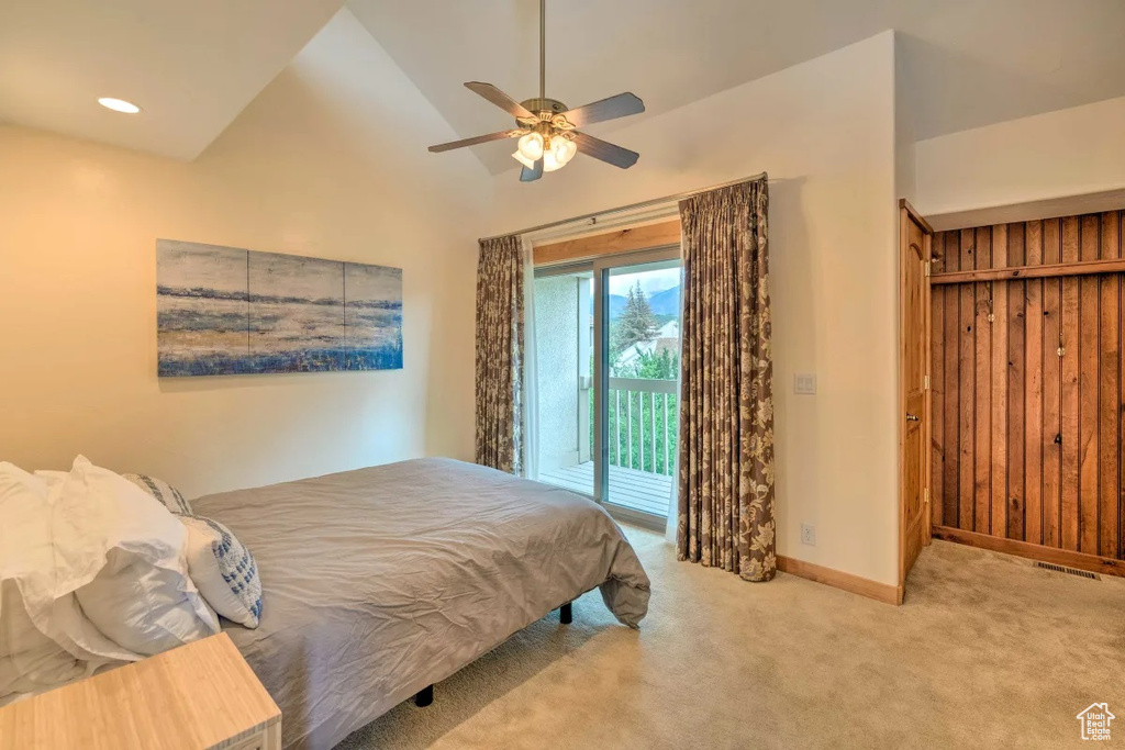 Carpeted bedroom featuring high vaulted ceiling, ceiling fan, access to exterior, and wood walls