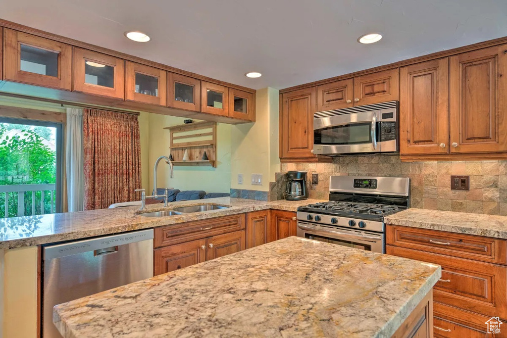 Kitchen with tasteful backsplash, stainless steel appliances, sink, and light stone countertops