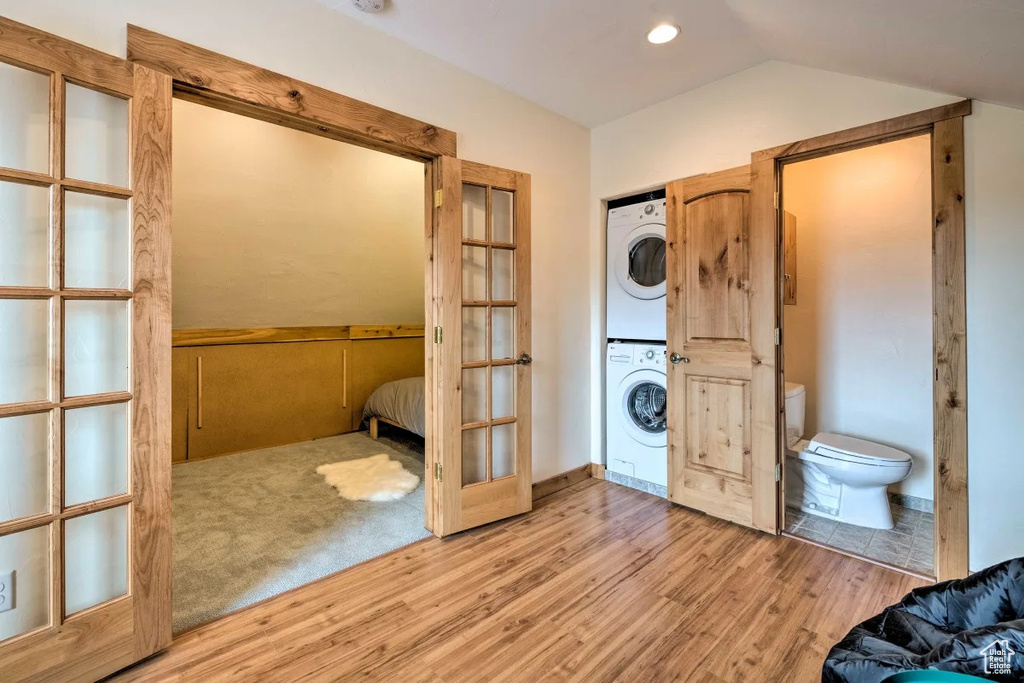Laundry room featuring light carpet and stacked washer and dryer
