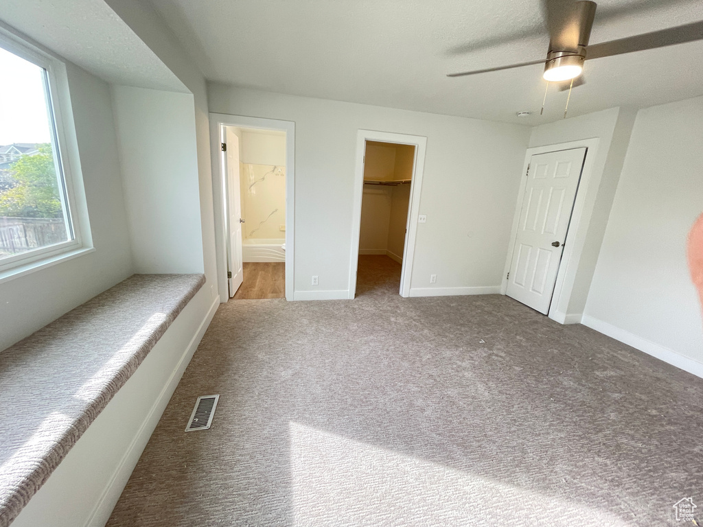Unfurnished bedroom with a spacious closet, ceiling fan, a closet, carpet floors, and connected bathroom