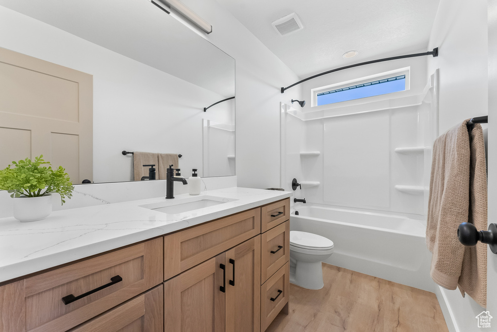 Full bathroom with washtub / shower combination, toilet, vanity, and hardwood / wood-style floors