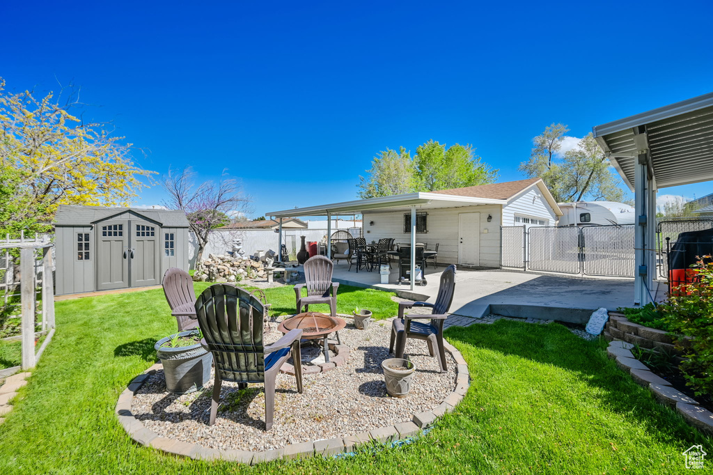 View of yard with a patio, a fire pit, and a storage shed