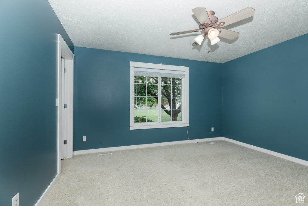 Unfurnished room featuring carpet, ceiling fan, and a textured ceiling