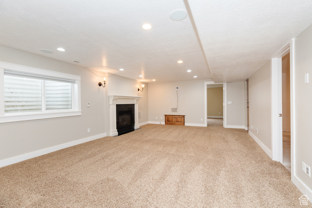 Unfurnished living room with a textured ceiling and carpet floors