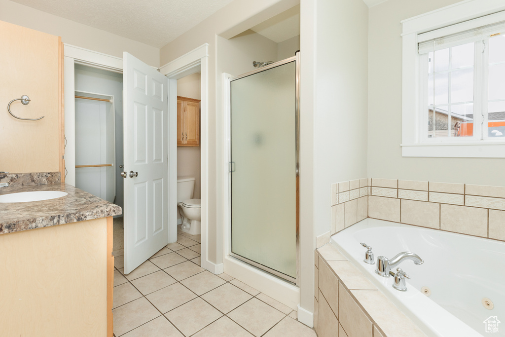Full bathroom featuring vanity, tile flooring, toilet, a textured ceiling, and plus walk in shower