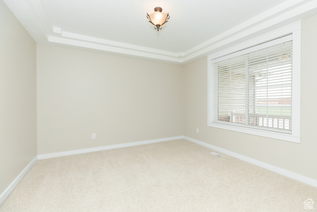 Carpeted empty room featuring a tray ceiling