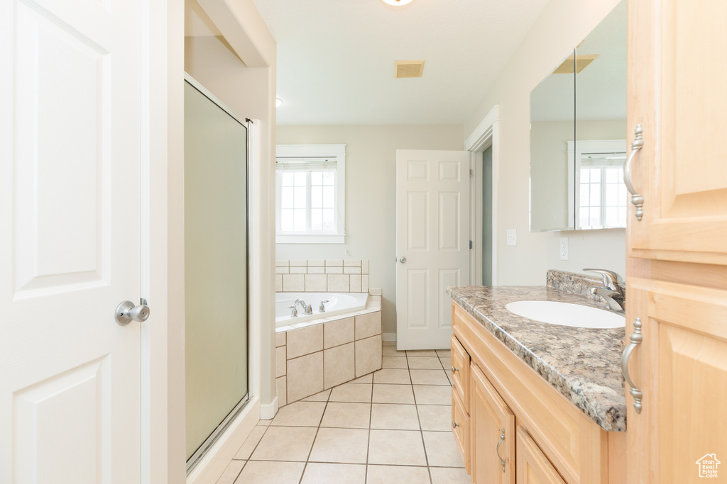 Bathroom with plenty of natural light, independent shower and bath, vanity, and tile flooring