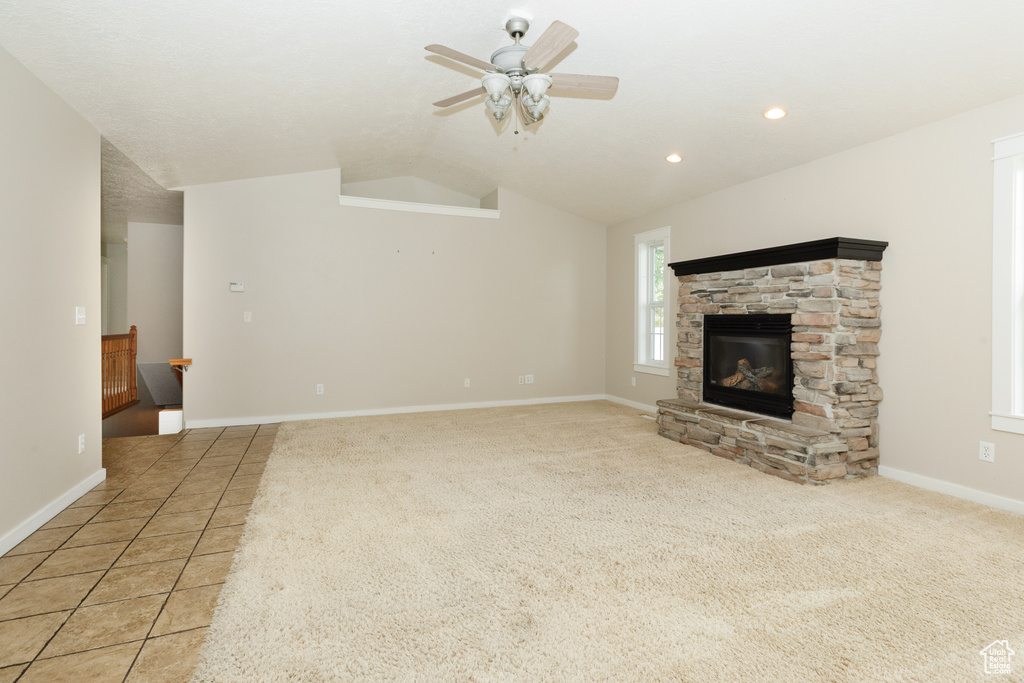Unfurnished living room with lofted ceiling, light carpet, ceiling fan, and a fireplace