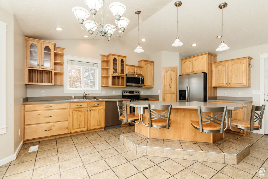 Kitchen with a center island, sink, decorative light fixtures, lofted ceiling, and stainless steel appliances