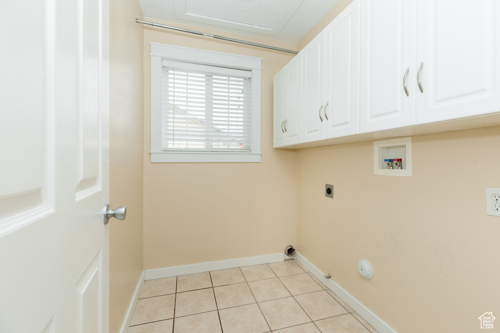 Washroom with cabinets, light tile floors, electric dryer hookup, hookup for a gas dryer, and washer hookup