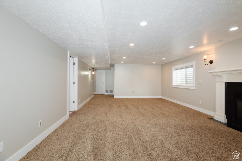 Unfurnished living room featuring carpet floors and a textured ceiling
