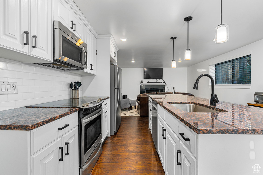 Kitchen with white cabinets, sink, backsplash, dark wood-type flooring, and stainless steel appliances