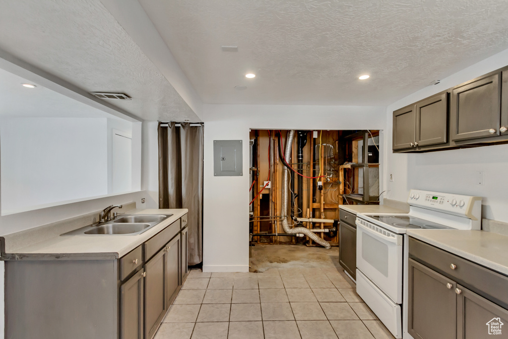 Kitchen with white electric stove, a textured ceiling, light carpet, and sink