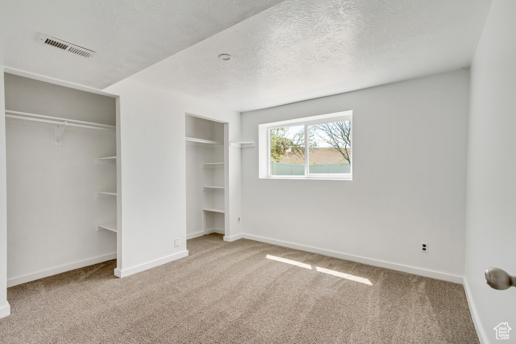 Unfurnished bedroom featuring a textured ceiling and carpet flooring