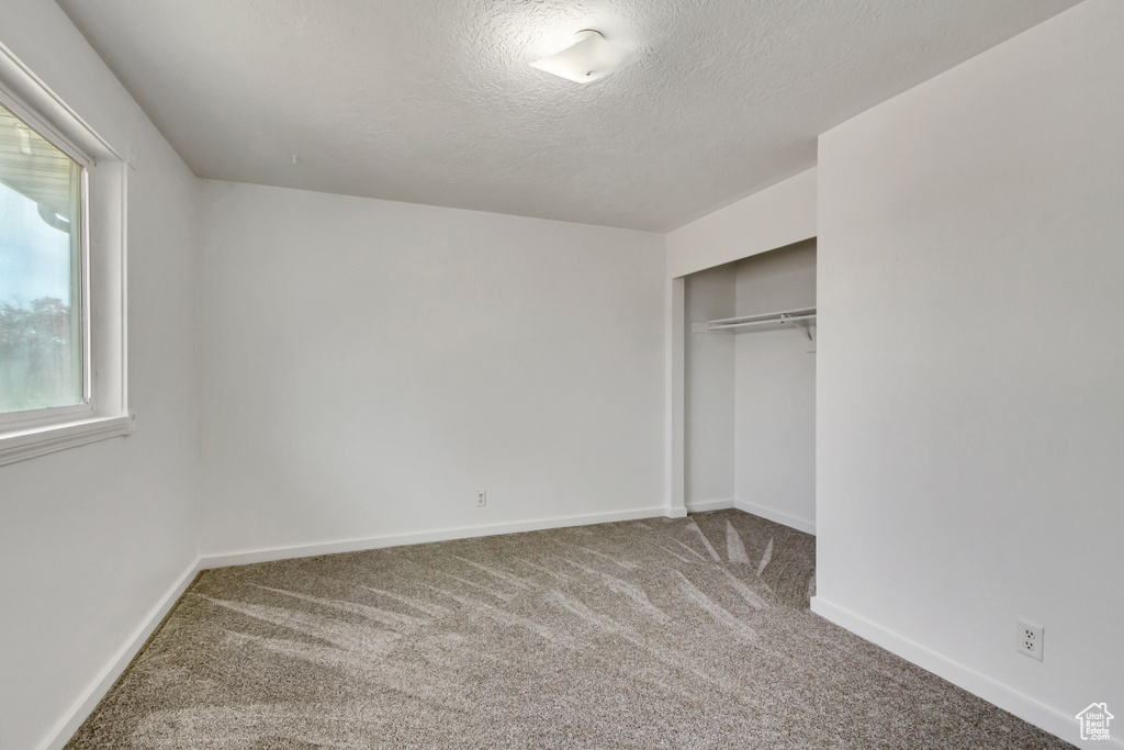 Unfurnished bedroom with a closet, a textured ceiling, and carpet floors