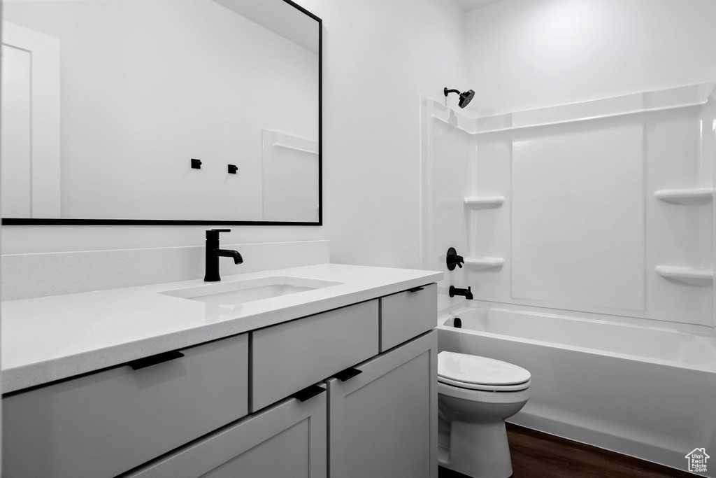 Full bathroom with vanity, shower / tub combination, toilet, and hardwood / wood-style flooring