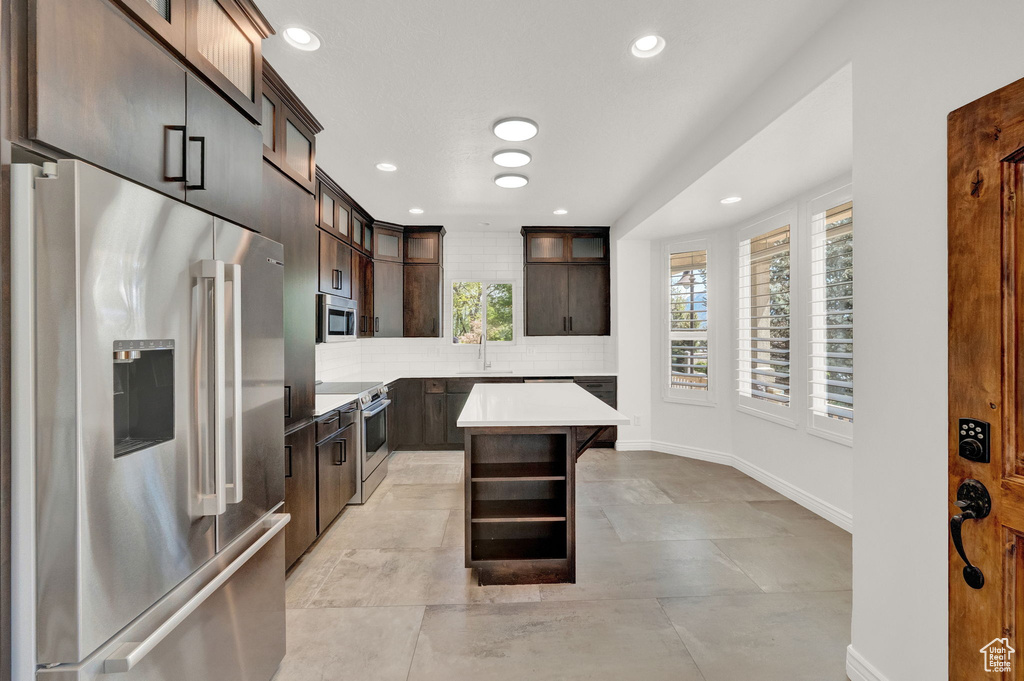 Kitchen with a kitchen island, tasteful backsplash, light tile floors, and stainless steel appliances