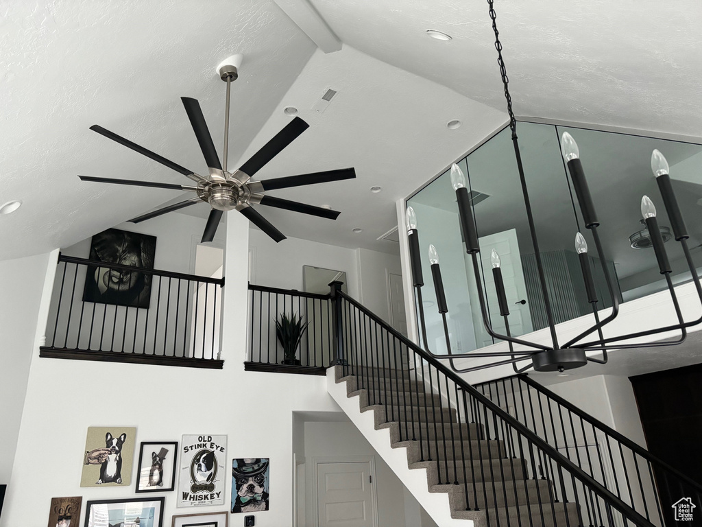 Stairway with ceiling fan and a towering ceiling
