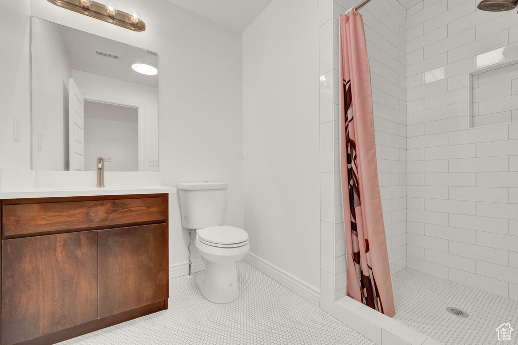 Bathroom featuring walk in shower, toilet, tile floors, and vanity