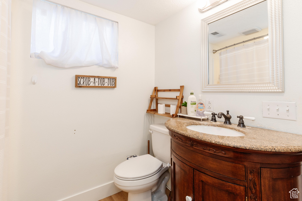 Bathroom featuring hardwood / wood-style flooring, toilet, and oversized vanity