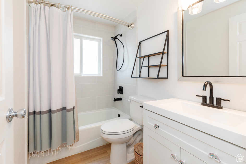 Full bathroom featuring shower / tub combo, toilet, oversized vanity, and hardwood / wood-style floors