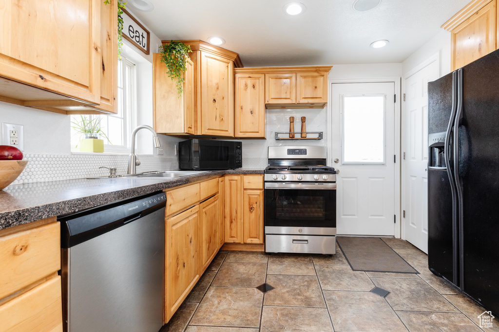 Kitchen featuring a wealth of natural light, tile floors, black appliances, and sink