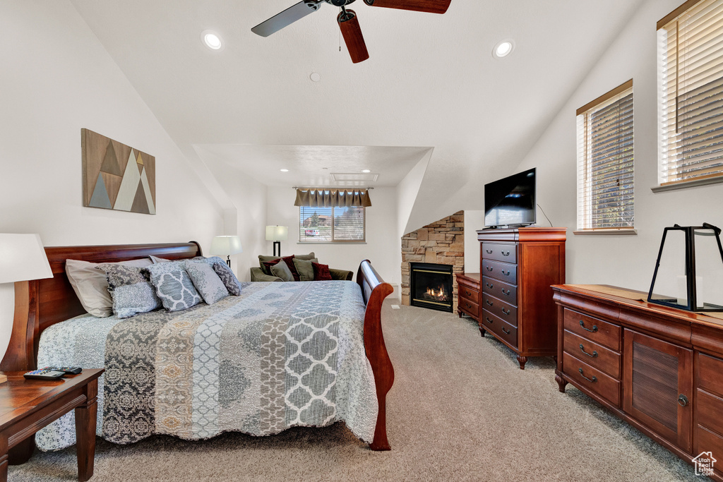 Bedroom with a stone fireplace, carpet, ceiling fan, and vaulted ceiling