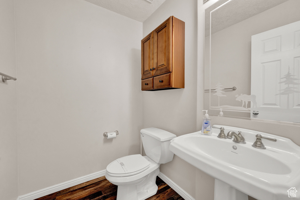 Bathroom featuring sink, a textured ceiling, wood-type flooring, and toilet