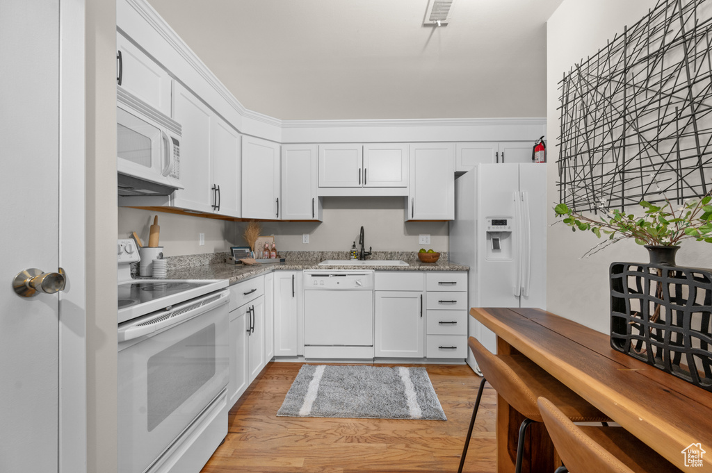 Kitchen with white cabinetry, light hardwood / wood-style flooring, white appliances, and sink