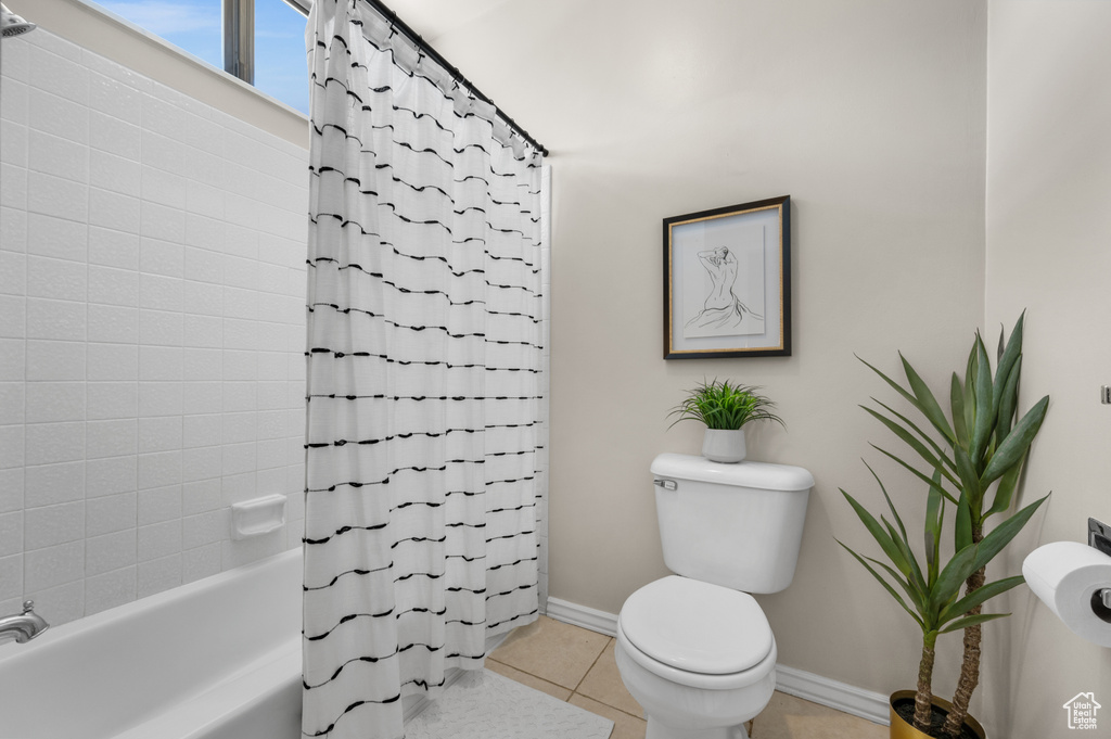 Bathroom with toilet, tile flooring, and shower / tub combo with curtain
