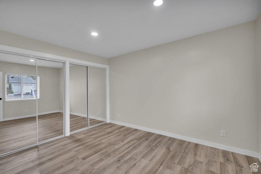 Unfurnished bedroom featuring light hardwood / wood-style flooring and two closets