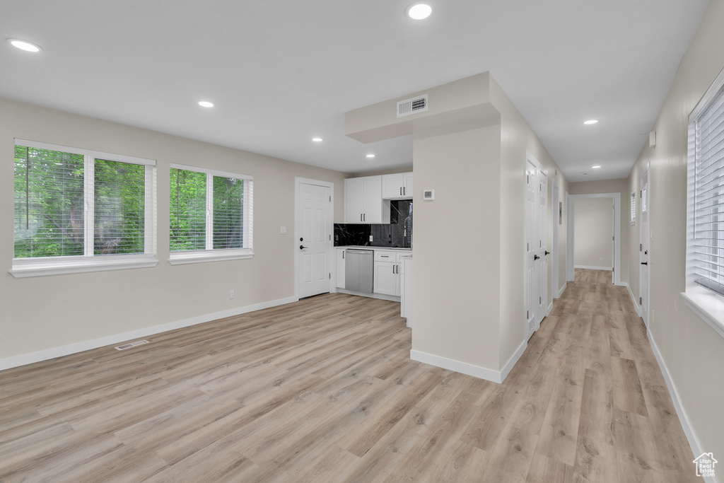Kitchen with backsplash, light hardwood / wood-style floors, dishwasher, and white cabinets