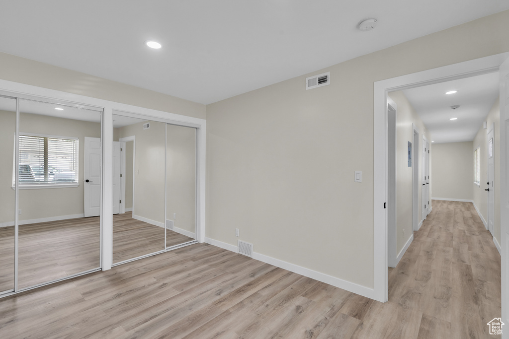 Unfurnished bedroom with light hardwood / wood-style flooring and multiple closets