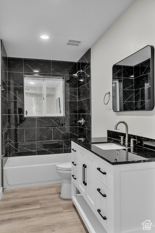Full bathroom with vanity, hardwood / wood-style flooring, toilet, and tiled shower / bath