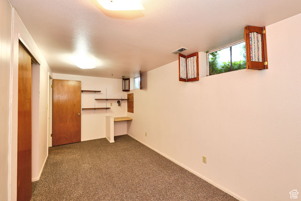 Basement with carpet flooring, built in desk, and a textured ceiling