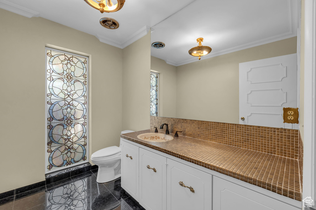 Bathroom with ornamental molding, tile floors, toilet, and large vanity