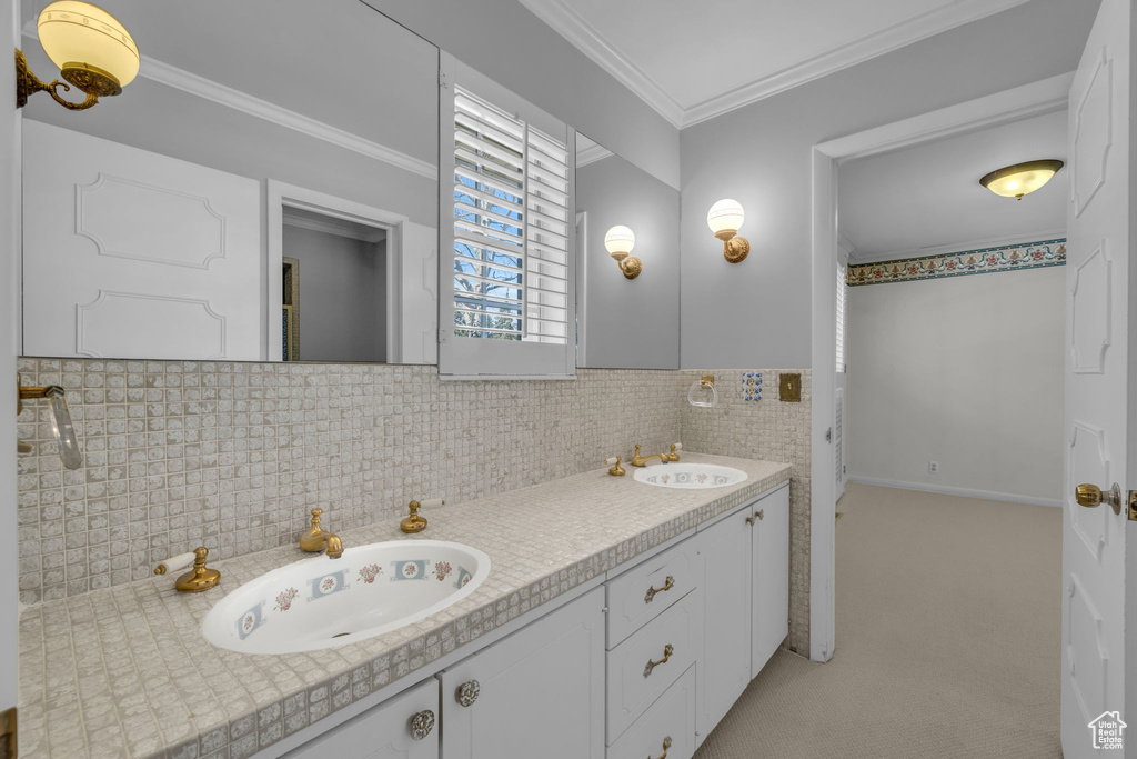 Bathroom with ornamental molding, tile walls, tasteful backsplash, and dual vanity