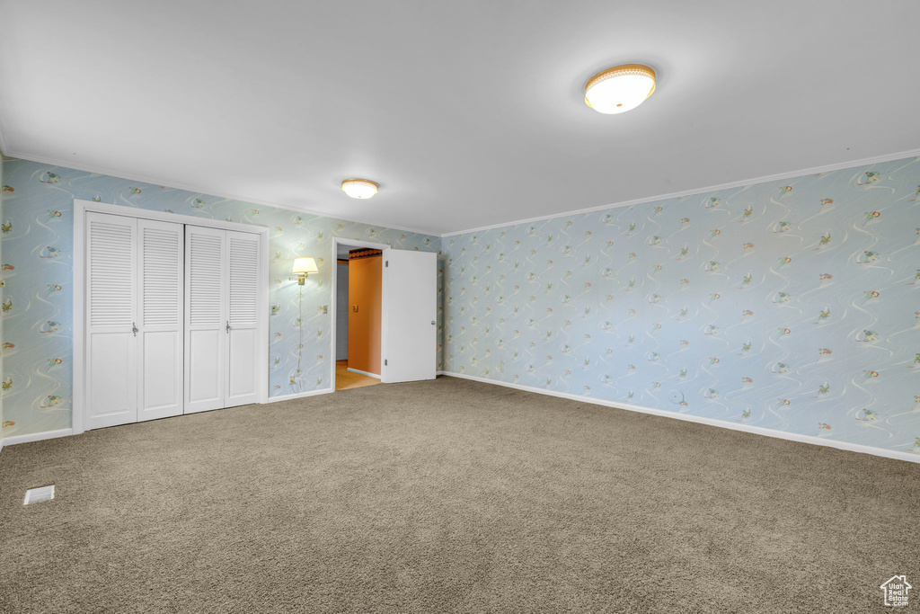 Unfurnished bedroom with a closet, carpet floors, and crown molding