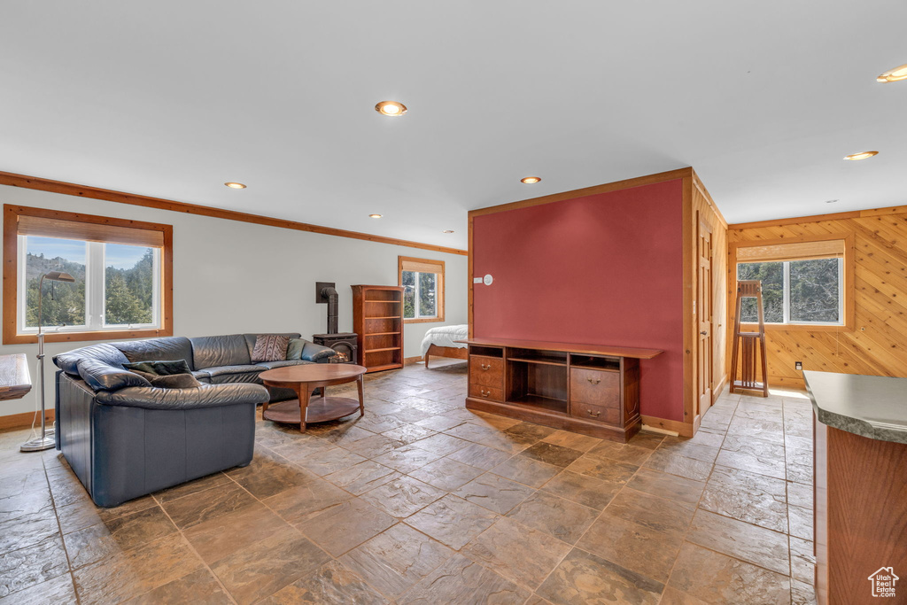 Living room featuring a wealth of natural light, crown molding, wooden walls, and tile flooring