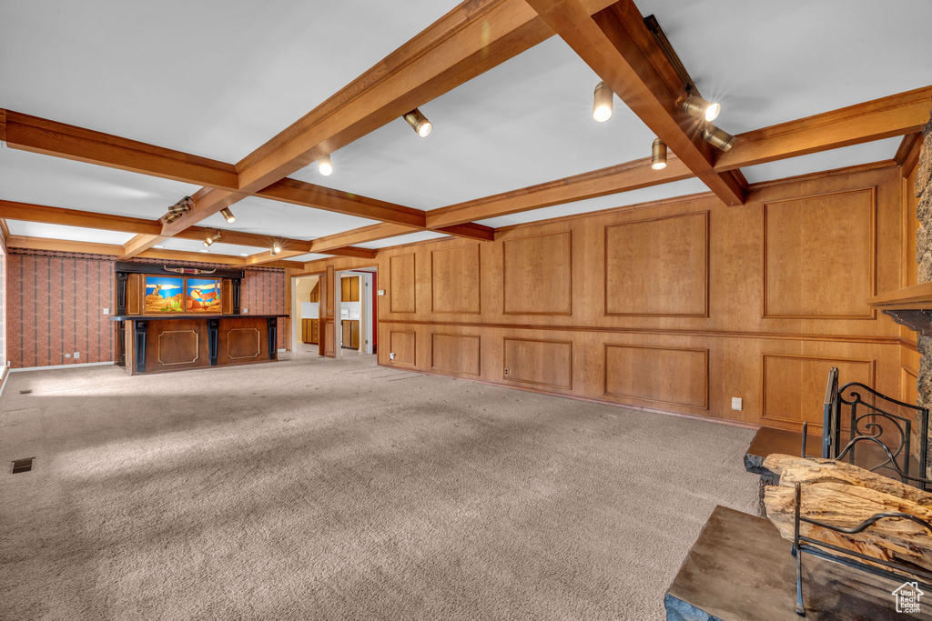 Living room with beamed ceiling, wooden walls, light carpet, and coffered ceiling