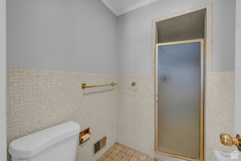 Bathroom featuring an enclosed shower, toilet, tile floors, and tile walls