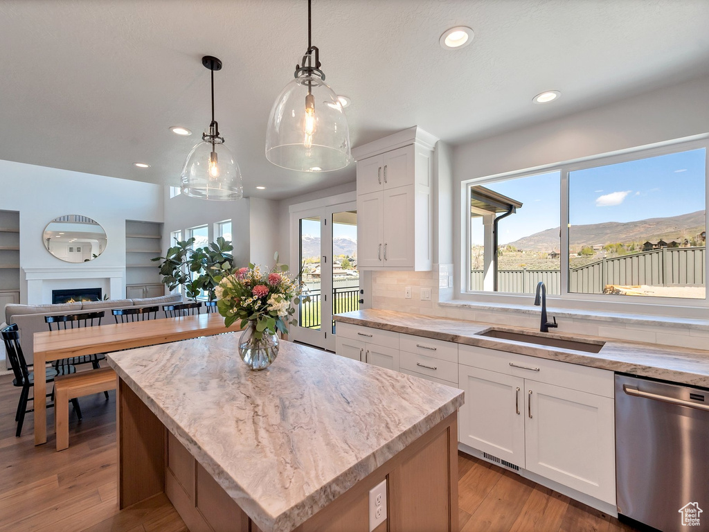Kitchen featuring a center island, dishwasher, tasteful backsplash, and light wood-type flooring