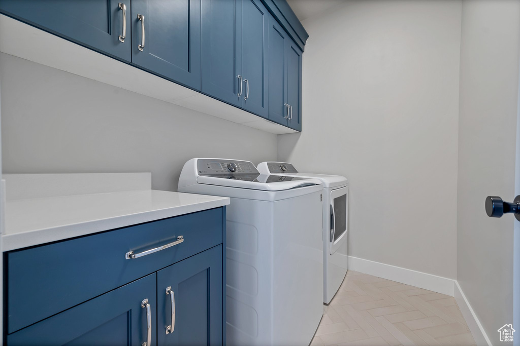 Washroom with cabinets, light parquet flooring, and washer and clothes dryer