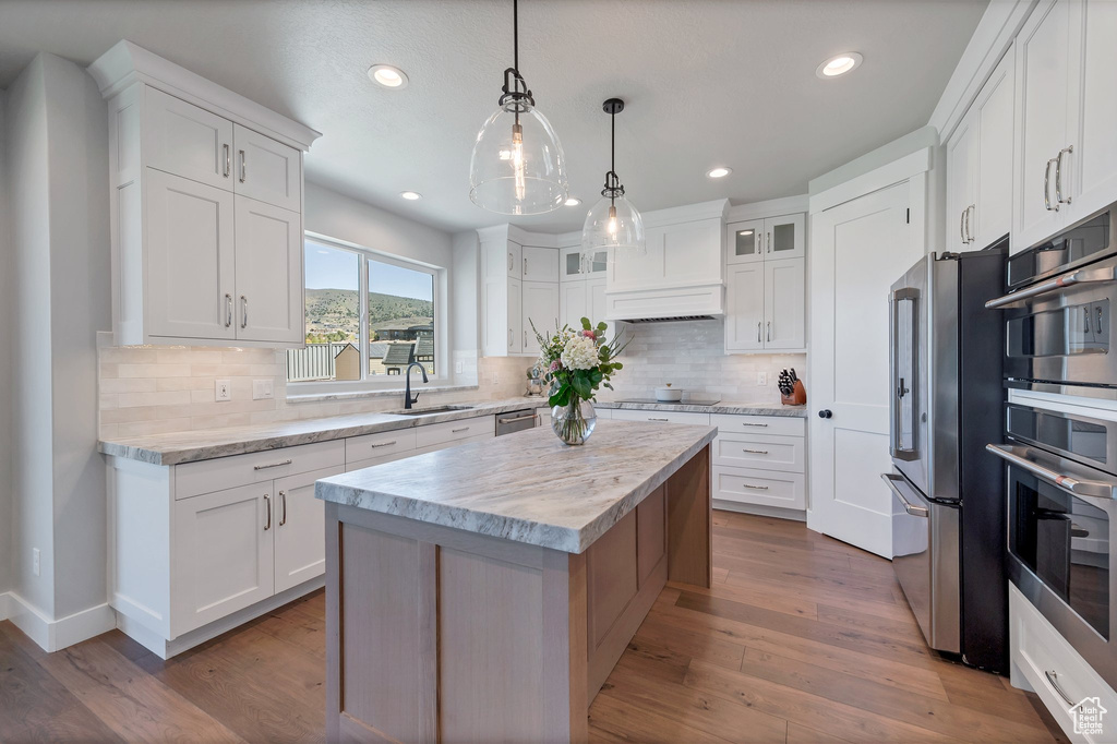 Kitchen featuring white cabinets, sink, tasteful backsplash, and hardwood / wood-style flooring