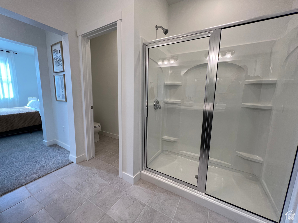 Bathroom featuring a shower with shower door, tile floors, and toilet