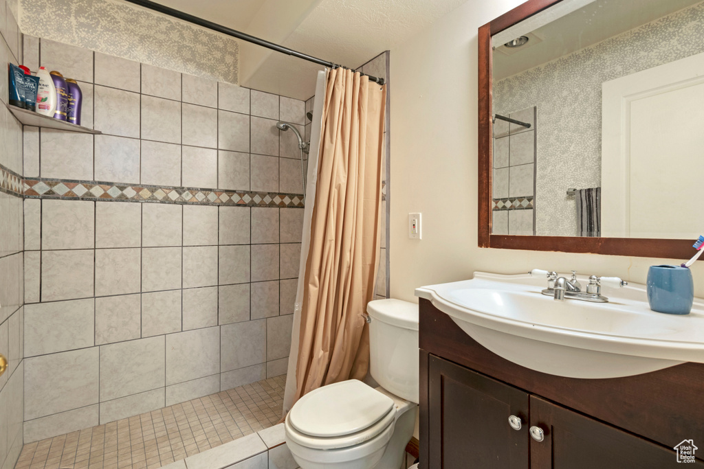 Bathroom with vanity with extensive cabinet space, toilet, a textured ceiling, and a shower with curtain