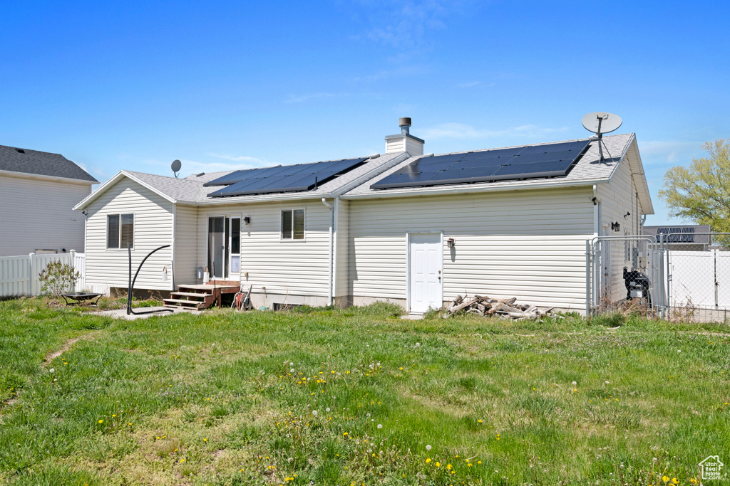 Rear view of house featuring solar panels and a lawn