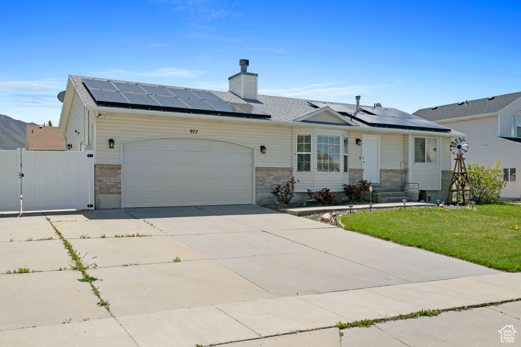 Ranch-style house with a garage, solar panels, and a front yard