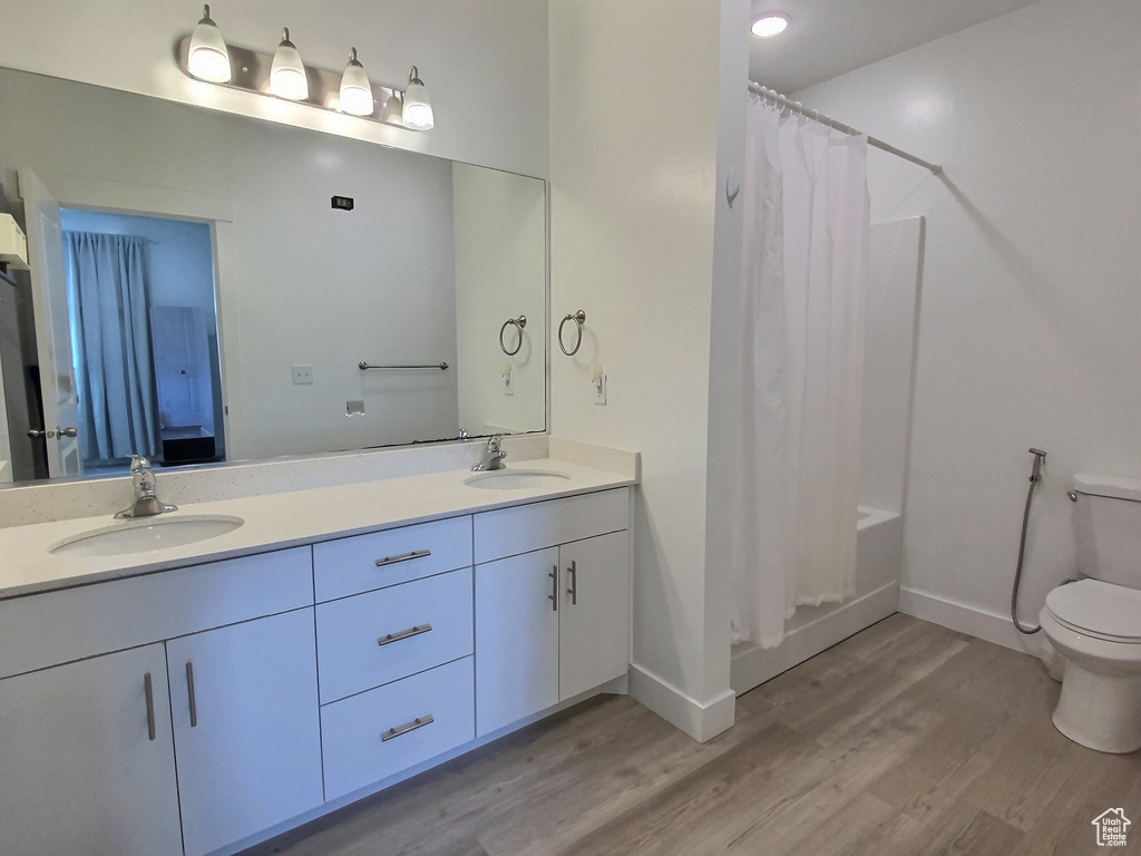 Bathroom featuring oversized vanity, hardwood / wood-style floors, toilet, and double sink